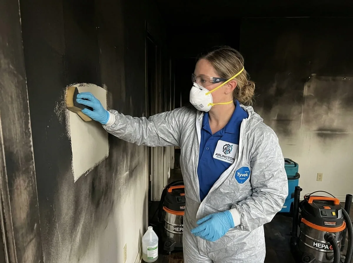 Technician cleaning soot residue from a wall surface after a residential fire